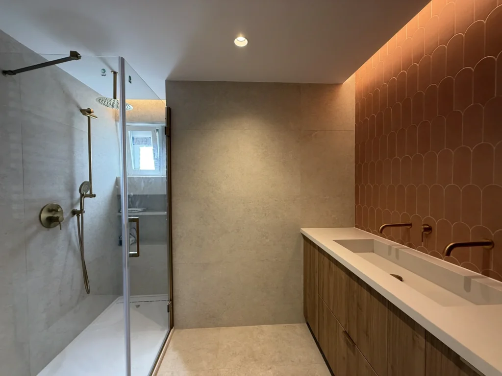 Ducha walk-in en reforma integral cerca de la Gran Vía de Bravo Murillo, con mampara cristal y azulejos rosados.